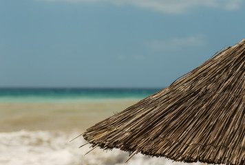 Fototapeta na wymiar beach umbrellas from natural materials against the sea. Beach vacation. Holidays at sea. travels. beach decor