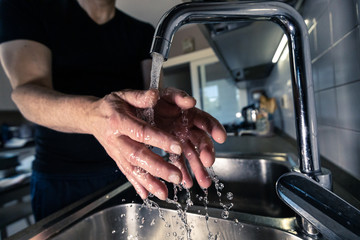 Uomo che si lava le mani in cucina sul lavello