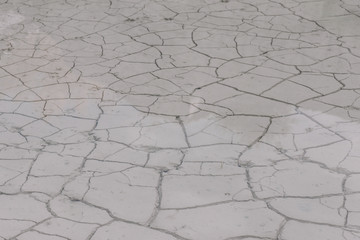 old abandoned limestone quarry flooded with water. White earth in cracks, covered with water. Natural background texture