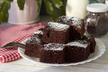 Pieces of chocolate cake on a white plate and a red and white checkered napkin. Dessert, Milk and Chocolate Drops