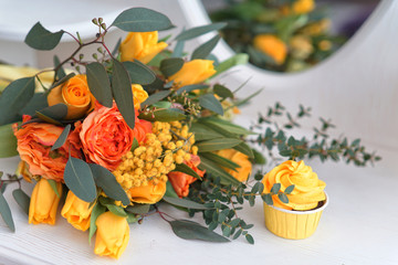 yellow cake on the dressing table with a mirror with a bouquet of their yellow, green and red flowers