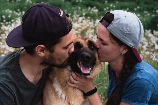A guy and a girl kiss and hug the dog on both sides. A man, a woman, and a German shepherd. Family photo session with a dog.