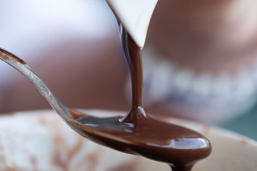 detail of liquid chocolate spilled from a container to a teaspoon