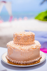 Obraz na płótnie Canvas Tropical wedding cake for bride and groom to cut during destination wedding marriage outdoor ceremony on the sandy beach in Dominican republic 