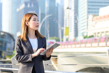 Fototapeta premium Young Asian business woman using laptop working in urban city. Concept of research, telelcommunication and technology
