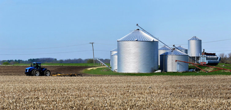 ROSCOE, ILLINOIS - May 2,2020: New Holland T9.390 tractor pulling a landoll 855 Finisholl cultivator with grain storage bins
