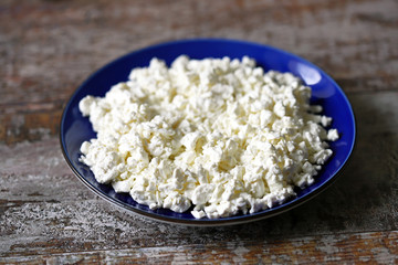 Selective focus. Macro. Organic cottage cheese in a blue plate. Fresh grained cottage cheese. Healthly food. Keto diet.