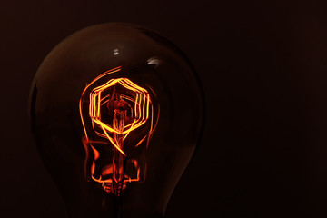 retro halogen lamp with incandescent tungsten filament close-up on a dark background.