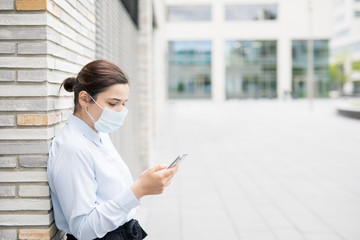 Frau mit Smartphone macht Pause vor Bürogebäude auf Campus oder Technologiepark.  Studentin in Vorlesungspause.