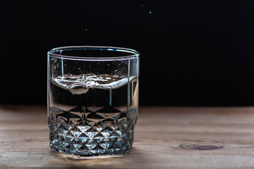 glass with poured water, transparent on a wooden table