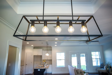 Hanging retro black metal iron chandelier lighting fixture with vintage bulbs hanging in a dining...