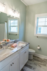 Small green guest bathroom with green walls and a gray and white tiled floor in a new construction house