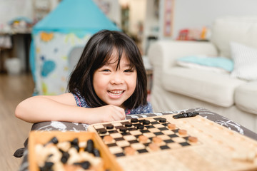 Fototapeta premium Asian kid girl and mother stay at home lockdown from covid-19 coronavirus crisis are playing chess while spending time together at home.Smart kid home school kid with mom.Stay home Stay safe with mom.