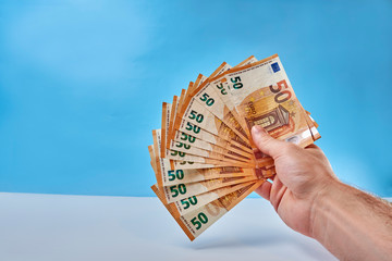 Hand holds 50 euro banknotes in a fan.