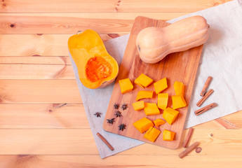 Butternut squash,  pumpkin pieces and spices on wooden background. Top view, copy space.