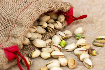 Roasted salted pistachio nuts in nutshell in the textile bag on light background.