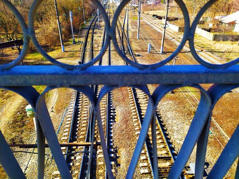 View of the railway over the iron metal railings from the bridge.
