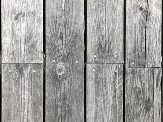 Old vertical wooden planks background, bleached white by the sun. Screws along the center.