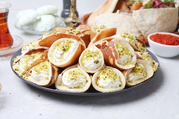 Traditional Arabic Dessert Qatayef With Cream And Nuts On Table With Meals. Ramadan Food Concept. Side View.