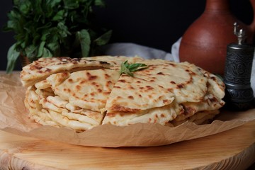 Caucasian Flat Bread With Filling (Chudu, Botishi, Hychin) With Mashed Potato And Cottage Cheese On Wooden Board With Herbs, Clay Jar. Side View, Close Up.