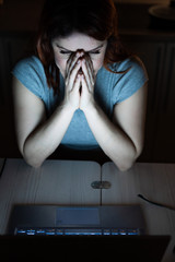 woman works overtime. A student studying at a laptop at night in the dark. The girl is worried...