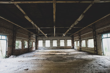Old abandoned factory building with huge windows and dirty floor