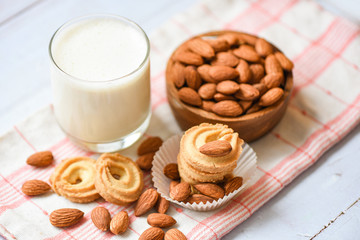 almond milk glass and cookie for breakfast health food - almonds nuts on wooden bowl background