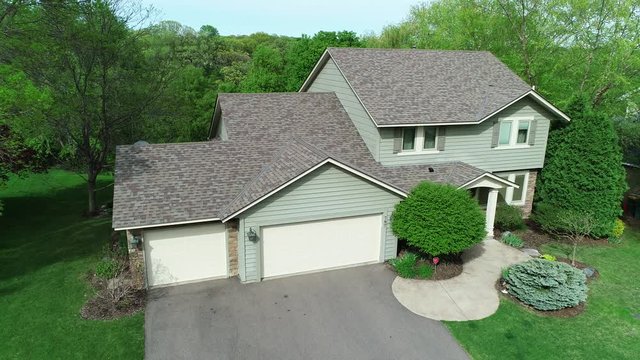 Drone aerial of a middle class suburban American home with typical modern design, a nice lawn and garage, filmed on a sunny summer or spring day.