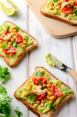 Vegan sandwich with avocado, nuts, vegetables and olive oil on white wooden table
