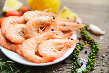 fresh shrimp on white plate with ingredients herb and spices - cooking seafood shrimps prawns served on a wooden table background