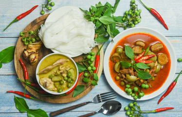 Set of Thai food green curry on soup bowl and red curry on plate with thai rice noodles vermicelli ingredient herb vegetable on wooden background green curry chicken cuisine asian food on the table