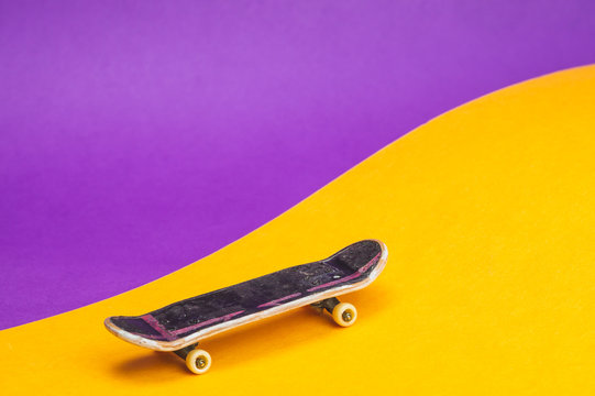 Small skateboard on color background. tiny skate for fingers. fingerboard close up. home leisure concept