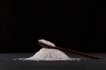 Glutamic acid monosodium salt in a wooden spoon on a dark background. Msg. Food additive E621....