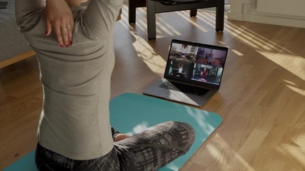Fitness coach teaching yoga online to group of people. People practicing yoga with trainer via video conference.
