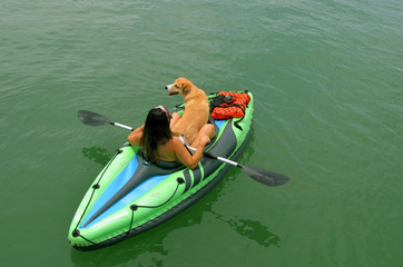 Overhead view of a young woman and her pet dog in a one place inflatable kayak.