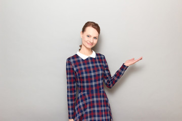 Portrait of cheerful young woman pointing with hand at copy space