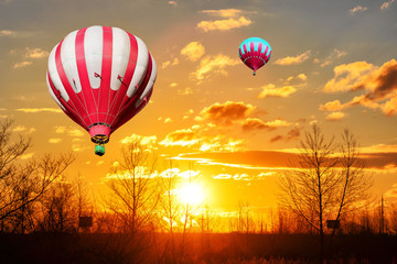 Red and white hot air balloons on the background of bright orange sunset.
