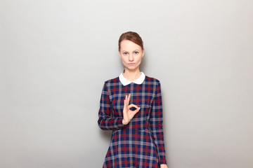 Portrait of serious focused young woman showing okay gesture or zero