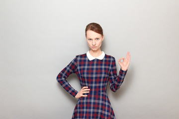 Portrait of serious focused young woman showing okay gesture or zero