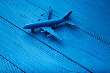 Figure passenger plane on blue, textured wooden background. Top view. Concept of travel