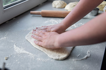 Preparation of the dough for baking, freezing, sculpting and other food blanks - a large piece of the dough is on the table and the chef cuts out small circles on it with an iron shape. Moulding