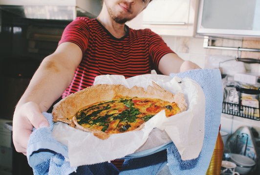 man holding home cooked meal and smiling in the kitchen