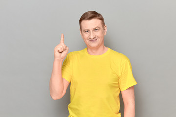 Portrait of happy cheerful mature man raising index finger and smiling