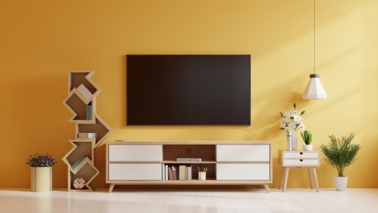 TV on cabinet in modern living room with lamp,table,flower and plant on yellow wall background.