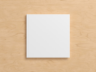 Blank square book cover mock up on wooden background. View directly above. 3d illustration