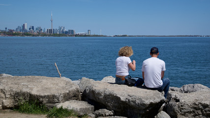 couple sitting on rocks with Toronto city as background