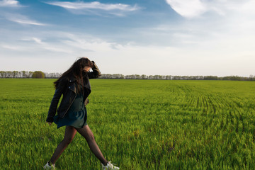 A girl in a medical mask runs or walks on a green field. Quarantine spring summer. coronavirus. COVID 19. Flu virus, colds