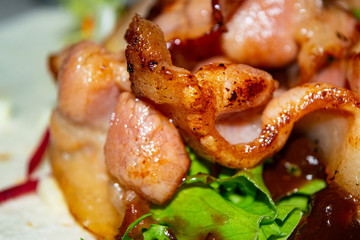 Leafy salad, sliced vegetables, sauce and fried bacon slices on pita bread are the basis for homemade Shawarma. Close up.