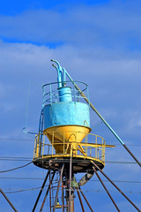 large color grain bin bunker (dispenser and dryer) behind the wires at elevator on blue sky in sunny day, modern technology