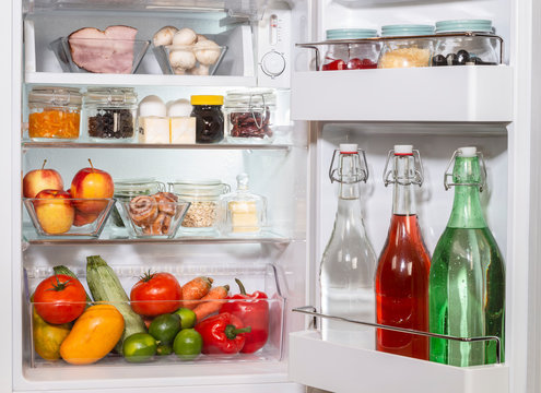 Refrigerador abierto con alimentos en recipientes de vidrio, libre de plasticos